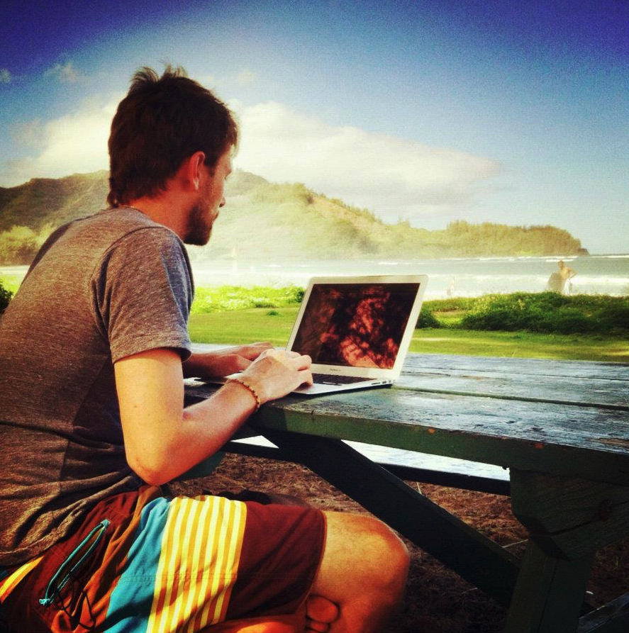 Bret James working on a laptop beside the ocean in Kauai, Hawaii